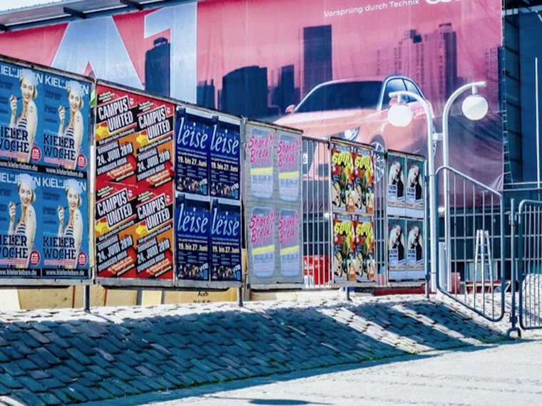 Gestaffelte Plakate an einer Plakatwand während der Kieler Woche